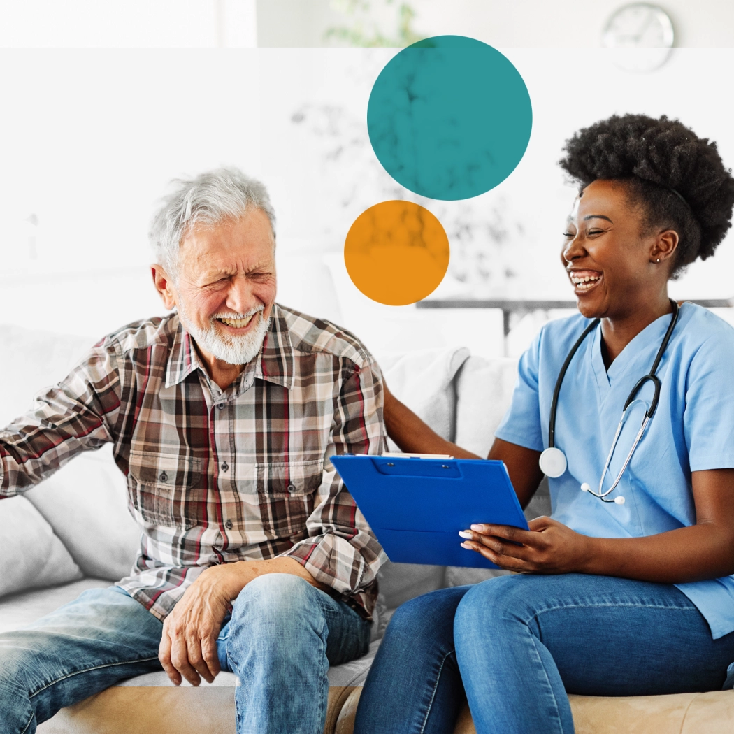 Elderly man laughing with a young female carer